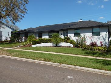 Charming white brick home featuring lush landscaping, solar panels, and a well-manicured lawn at 2709 Fairway View Dr, Valrico, FL 33596