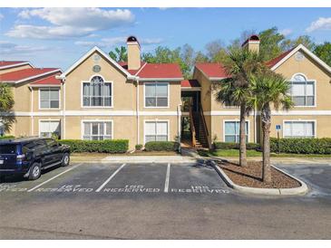 Two story tan condo building with red roof, palm trees, and reserved parking at 9481 Highland Oak Dr # 404, Tampa, FL 33647