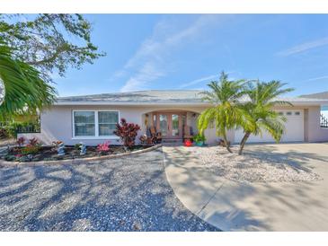 Charming single-story home featuring lush landscaping, a well-manicured lawn, and a welcoming entryway with double doors at 6324 Balboa Ln, Apollo Beach, FL 33572