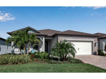 Beautiful single-story home featuring stone accents, manicured lawn, and a two-car garage at 8724 Ocean Tides Cv, Parrish, FL 34219