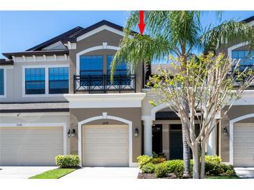 A charming multi-story townhouse boasting a private garage and a quaint balcony with black iron railings at 11648 Crowned Sparrow Ln, Tampa, FL 33626