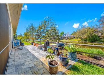 Relaxing back patio featuring a grill and a beautiful view of the tranquil waterway and the house across it at 2270 Spring Lake Ct, Clearwater, FL 33763