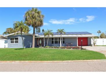 Charming single-story home with well-manicured lawn, palm trees, and solar panels against a clear blue sky at 4301 50Th S Ter, St Petersburg, FL 33711