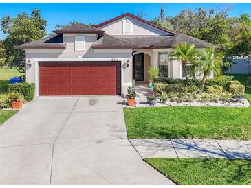 Beautiful single-story home with a well-manicured lawn, mature landscaping, and a two car garage at 5016 Bella Armonia Cir, Wimauma, FL 33598