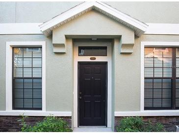 Charming front door with black paint, decorative trim, and well-kept landscaping, set between two black trimmed windows at 5710 Kingletsound Pl, Lithia, FL 33547