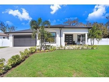 Charming single-story home featuring a manicured lawn, lush landscaping, and a two-car garage at 7403 Edgemere Rd, Tampa, FL 33625