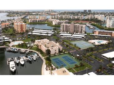 Wide aerial view of community featuring a pool, tennis courts, parking, waterway, and residences at 7910 Sun Island S Dr # 302, South Pasadena, FL 33707