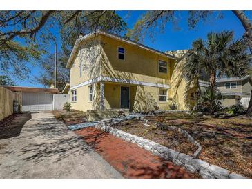 Charming two-story yellow home with a well-manicured front yard and detached garage at 2073 Madrid N Ct, Clearwater, FL 33763