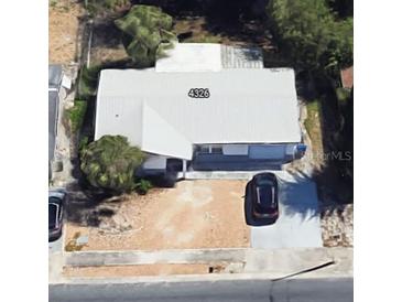 A simple house seen from above with a gravel driveway and ample parking spaces for multiple vehicles at 4326 Westwood Dr, Holiday, FL 34691