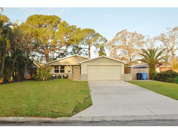 Charming single-story home with a well-manicured lawn, mature trees, and a two-car garage at 8708 Orient Ne Way, St Petersburg, FL 33702