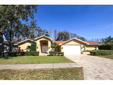 Inviting single-story home featuring a paver driveway, manicured landscaping, and a classic double-door entry at 9805 Hermosillo Dr, New Port Richey, FL 34655