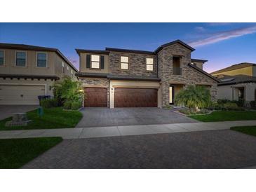 Stunning two-story home featuring a stone facade, three-car garage, and well-maintained landscaping at 12857 Satin Lily Dr, Riverview, FL 33579