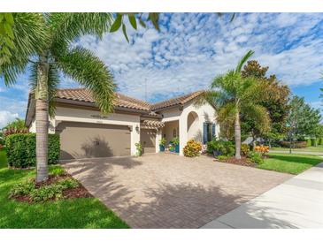 Charming home featuring a brick driveway, a two-car garage, and professionally landscaped garden with palm trees at 14315 Rolling Dune Rd, Lithia, FL 33547