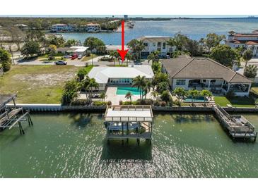 Waterfront home featuring a private dock, boat lift, and swimming pool on a sunny day at 5105 W Longfellow Ave, Tampa, FL 33629