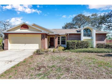 Charming single-story brick home with attached garage and a well-manicured lawn at 8137 Greenside Ln, Hudson, FL 34667