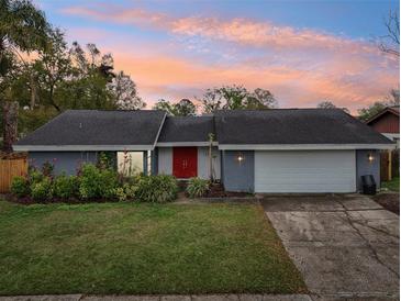 Charming single-story home with a gray exterior, vibrant red door, and a well-maintained front lawn at 15639 Bear Creek Dr, Tampa, FL 33624