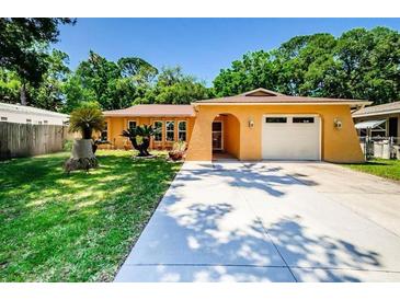 Charming one-story home with a well-manicured lawn, mature trees, and a spacious driveway leading to an attached garage at 7131 Wedgewood Dr, New Port Richey, FL 34652