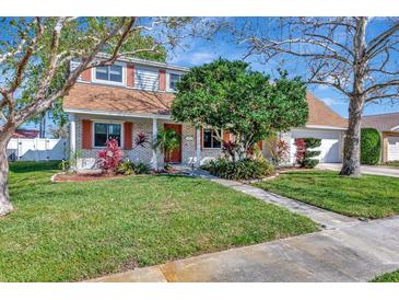 Charming two-story home with brick accents, lush landscaping, and a well-manicured lawn at 4711 Travertine Dr, Tampa, FL 33615