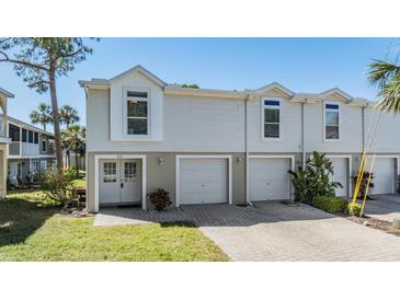 Charming townhome featuring a two-car garage, a well-manicured lawn, and a welcoming double-door entrance at 7631 Sailwinds Pass, Port Richey, FL 34668