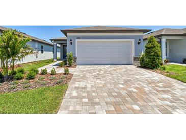 Beautiful single-Gathering home featuring a two-car garage and charming landscaping, plus a brick paver driveway and walkway at 9412 Coastline Way, Parrish, FL 34219