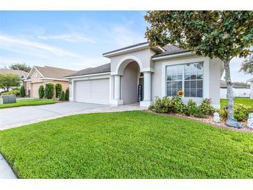 Charming one-story home featuring a well-manicured lawn, an arched entry, and a two car garage at 16313 Dinsdale Dr, Spring Hill, FL 34610
