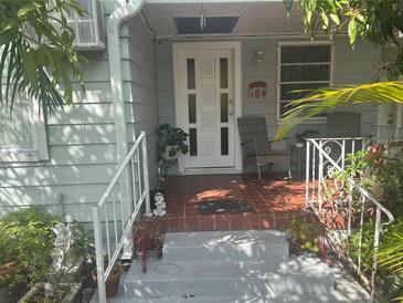 Inviting front porch with light-colored railing, stylish chairs, and a decorative front door at 2917 W Pine St, Tampa, FL 33607