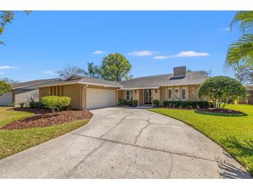 Charming single-story home boasts a brick facade, manicured lawn, and a curved driveway leading to an attached two-car garage at 4010 Priory Cir, Tampa, FL 33618