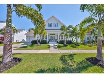 Charming two-story home with light blue shutters, well-manicured lawn, and decorative palm trees at 413 Islebay Dr, Apollo Beach, FL 33572