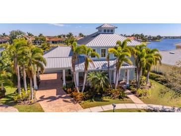 Beautiful two-story home featuring a metal roof, lush landscaping, and a brick driveway with a convenient porte-cochere at 5321 Fishersound Ln, Apollo Beach, FL 33572