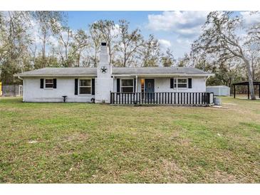Charming single-story home with a white brick facade, black shutters and a cozy front porch at 5419 Cyril Dr, Dade City, FL 33523