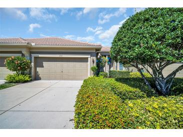 Inviting home exterior featuring a two-car garage, tiled roof, lush landscaping, and a well-maintained driveway at 2537 Gloriosa Dr # 2, Palm Harbor, FL 34684
