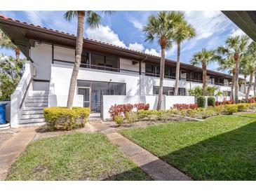 Charming two-story condo building with lush landscaping and mature palm trees at 3500 El Conquistador Pkwy # 242, Bradenton, FL 34210