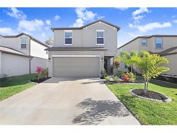 Charming two-story home featuring a well-manicured lawn, lovely landscaping, and a spacious driveway leading to a two-car garage at 36312 Garden Wall Way, Zephyrhills, FL 33541