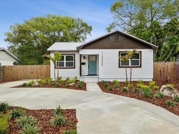 Charming home featuring a metal roof, freshly landscaped yard, and a stylish blue front door at 1008 E Norfolk St, Tampa, FL 33604