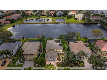 Stunning aerial view of a home near a serene lake with lush landscaping and neighboring houses at 2665 Lakebreeze N Ln, Clearwater, FL 33759