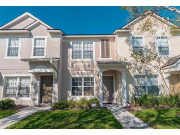 Inviting two-story townhome featuring a covered entryway, well-maintained lawn, and charming architectural details at 4535 Kennewick Pl, Riverview, FL 33578