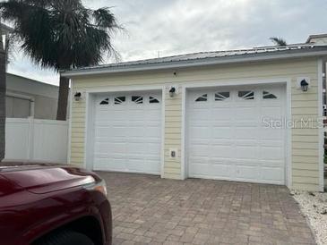 Detached two car garage with white doors and brick paved driveway at 19109 Gulf Blvd, Indian Shores, FL 33785
