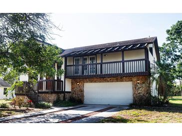 Two-story home showcasing a stone-clad garage, upper-level balcony, and charming curb appeal at 130 80Th Ne Ave, St Petersburg, FL 33702