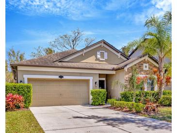 Charming single-story home with a two-car garage, stone accents, and lush landscaping under a bright blue sky at 1307 Garden Stone Ln, Brandon, FL 33510
