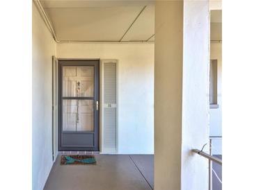 View of the front door to this residence with a decorative welcome mat and neutral facade at 19029 Us Highway 19 N # 1-22, Clearwater, FL 33764