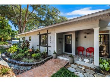Charming home featuring a landscaped front yard and a welcoming covered porch with red chairs at 3026 51St S St, Gulfport, FL 33707
