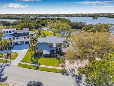 Stunning aerial view of a lovely home with a manicured lawn on a waterfront property with gorgeous scenery at 9011 Baywood Park Dr, Seminole, FL 33777