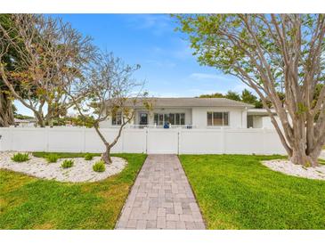 Charming single-story home with a well-manicured lawn, a white picket fence, and a brick walkway at 292 42Nd Ave, St Pete Beach, FL 33706