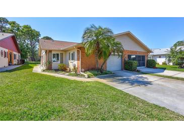 Charming home with a two-car garage, brick accents and mature landscaping with palm trees at 3210 Mcmath Dr, Palm Harbor, FL 34684
