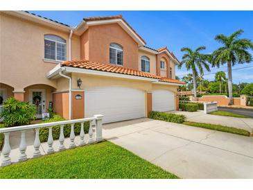Charming two-story townhome boasts a white garage door and decorative fence, surrounded by lush landscaping at 6345 Vista Verde E Dr, Gulfport, FL 33707