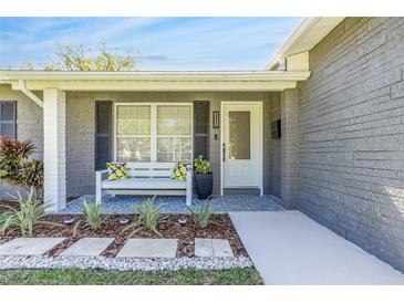 Charming front porch with white bench seating, decorative pillows, and well-maintained landscaping at 1842 Oklahoma Ne Ave, St Petersburg, FL 33703