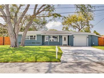 Charming one-story home with blue exterior paint, a well-manicured lawn, and a concrete driveway to the garage at 1466 Laconia W Dr, Clearwater, FL 33764