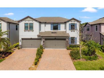 Charming two-story townhouse featuring a brick-paved driveway and a two-car garage at 4896 San Martino Dr, Wesley Chapel, FL 33543