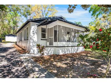 Charming bungalow with a screened front porch, white exterior, and mature landscaping at 126 Highland St, Brooksville, FL 34601