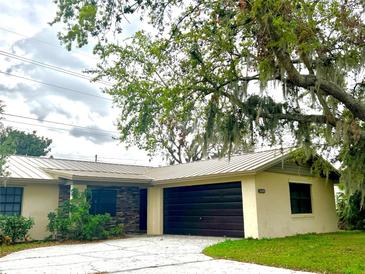 Charming single-story home with a metal roof, dark garage door, and stone facade detail at 3608 Oak Bark Ln, Brandon, FL 33511